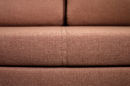 A close-up of a fragment of an expensive beige textile sofa in the room