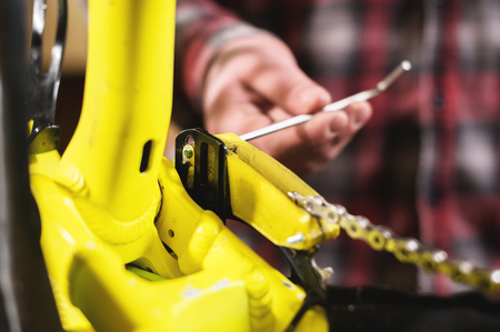Close-up maintenance of a mountain bike. Male hands adjust the chain tension. Technical condition...