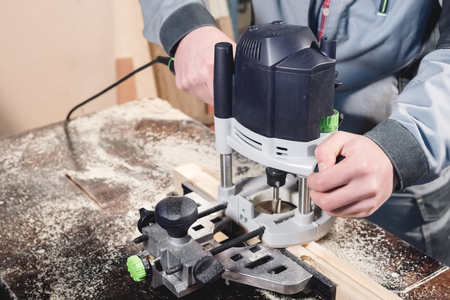 Close-up electric milling cutter in the hands of a worker in a home workshop. Starting a business. Craftsmanの写真素材