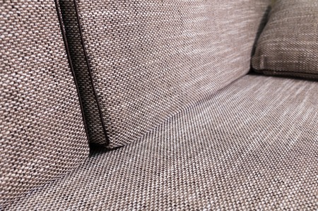 Close-up element gray-beige sofa with dark pillows. Premium new furniture