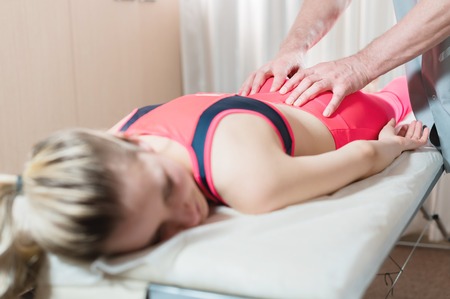 Girls spine base editing by a male physiotherapist of visceral massage. The hands of the doctor set...