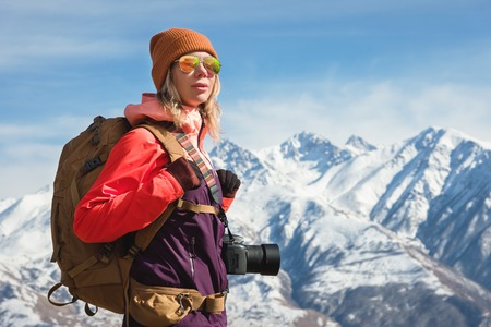 Portrait of photographer hipster tourist girl with a camera in sunglasses and a hat against the...
