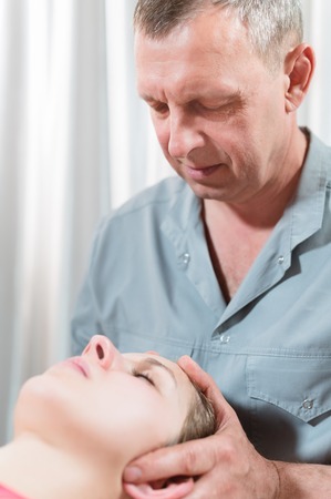 The visceral doctor is engaged in manual editing of the skull of a young girl. Alternative medicine. Health Prevention Conceptの写真素材