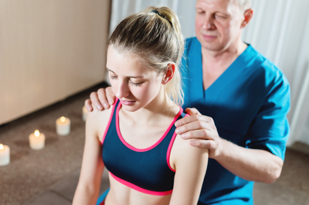 Male manual visceral therapist masseur treats a young female patient. Diagnosis of the shoulders and forearmsの写真素材