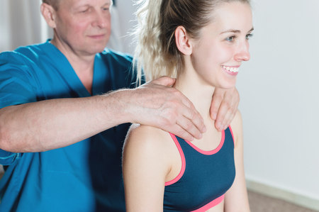 Male manual visceral therapist masseur treats a young female patient. Warm up the shoulders and neckの写真素材