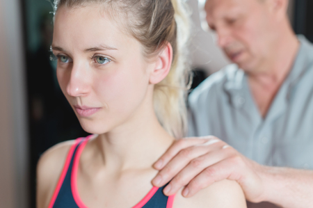 Male manual visceral therapist masseur treats a young female patient. Work with the back and shouldersの写真素材