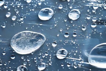 Close-up of raindrops of different sizes on the surface covered with cling film. Moisture weather and humidity conceptの写真素材