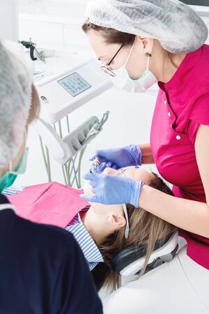 Close-up a young girl in a dentists chair undergoes a routine diagnosis after removing braces with cleaning and sizing. Stamatology in life and in the clinicの写真素材