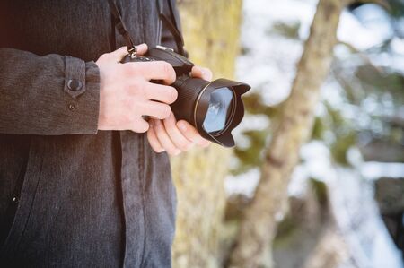 Close-up professional digital mirror camera in male hands in the winter forest. Photo travel conceptの写真素材