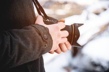 Close-up professional digital mirror camera in male hands in the winter forest. Photo travel concept