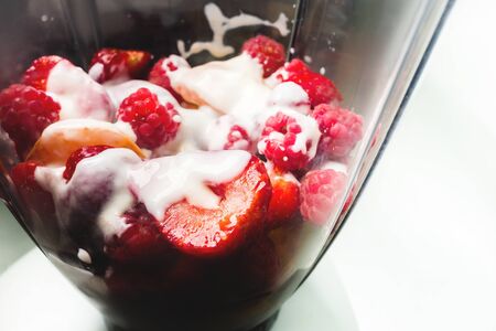 Closeup strawberry and apricot lie in a blender poured with fresh yogurt or milk. Healthy and fresh food. The concept of vegetarianismの写真素材