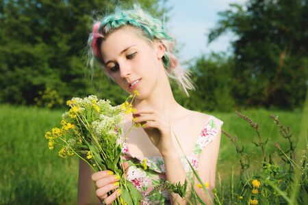 Portrait of a young happy smiling girl in a cotton dress with a bouquet of wildflowersの写真素材