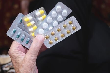 Closeup of a tablet on the hands of an old woman. The concept of choosing medication in old ageの写真素材