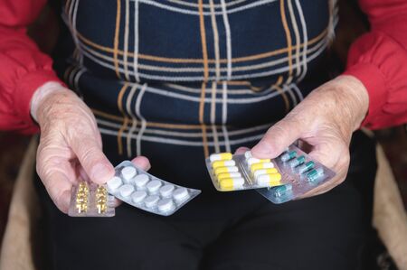 Closeup of a tablet on the hands of an old woman. The concept of choosing medication in old ageの写真素材