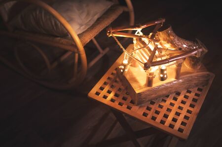 Close-up wooden lampshade with backlight and rocking chair in a poorly lit bedroom at night. Home comfort conceptの写真素材