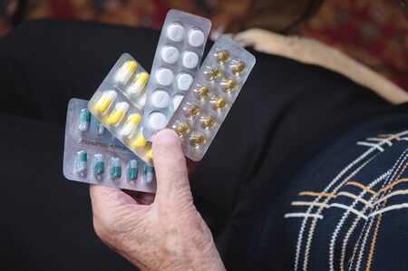 Closeup of a tablet on the hands of an old woman. The concept of choosing medication in old age.