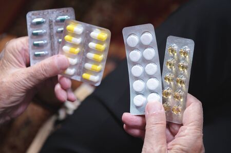 Closeup of a tablet on the hands of an old woman. The concept of choosing medication in old age