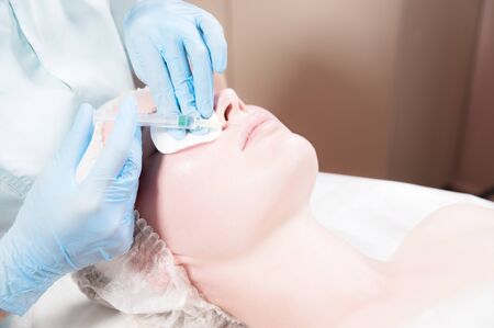 Close-up Attractive young woman gets anti-aging face injections. She lies calmly in a clinic or...