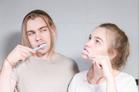 Young couple in bath brush teeth together, looking in mirror. Close-upの写真素材