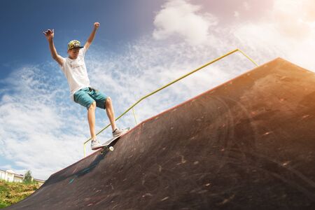 Portrait of a young skateboarder doing a trick on his skateboard on a halfpipe ramp in a skate park...