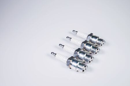 Subject shooting on a gray background. new four spark plugs, spare parts for a gasoline engine. The concept of new auto parts and maintenance.の写真素材