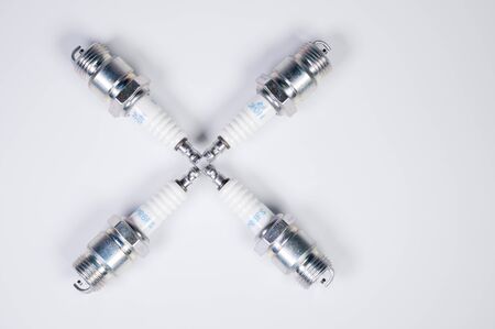 Subject shooting on a gray background. new four spark plugs, spare parts for a gasoline engine. The concept of new auto parts and maintenanceの写真素材