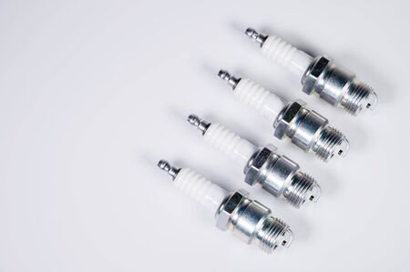 Subject shooting on a gray background. new four spark plugs, spare parts for a gasoline engine. The concept of new auto parts and maintenance.の写真素材