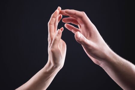 A close-up of two hands male and female gently touch each other. The concept of tremulous rejection...