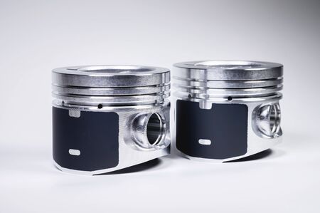 Two new piston of the internal combustion engine with dust on the sides on a gray gradient...