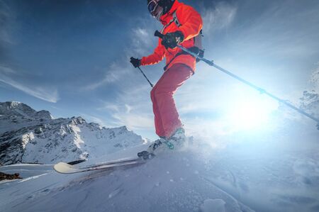 close up Skier rides on a snowy slope on a sunny day at sunset against the backdrop of the mountains. The concept of winter skiingの写真素材