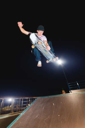 A young skater at night in a skatepark does the trick on the railing. X-ray culture nightlife...