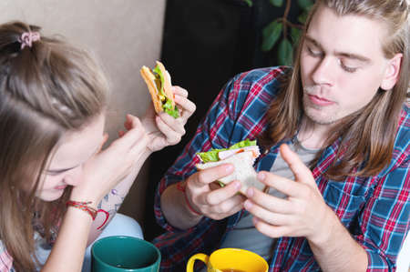 A young attractive couple has breakfast in their home kitchen. They feed each other and laugh. The concept of healthy eating in the family and happinessの写真素材