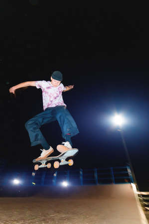 A young skater does the trick of sliding at night in a skatepark. The concept of night leisure and youth culture at nightの写真素材