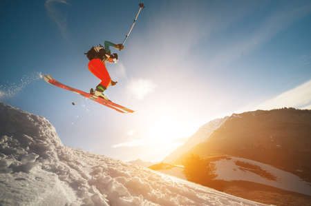Professional athlete young male skier with a backpack and in a ski mask makes a trick in flight...