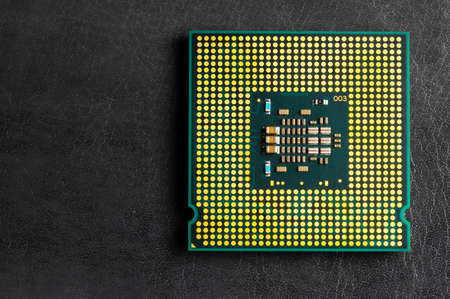 The microprocessor processor of the CPU of a computer or laptop lies on a dark matte surface....