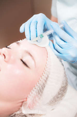 Woman professional beautician conducts an injection of botox or hyaluronic acid to a client in a beauty salonの写真素材
