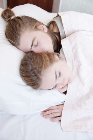 Young loving caucasian couple man and woman sleeping in bed in bedroomの写真素材