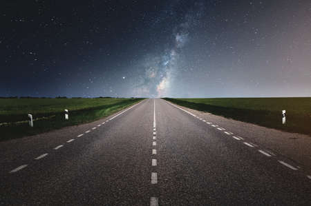 Straight asphalt country road under clear night sky with stars and milky way in summerの写真素材