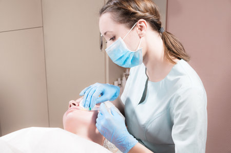 Professional beautician conducts an injection of botox or hyaluronic acid to a client in a beauty...