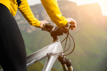 Close-up of woman cyclist hand on handlebars of mtb bike outdoors in mountainsの写真素材