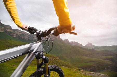 Close-up of woman cyclist hand on handlebars of mtb bike outdoors in mountainsの写真素材