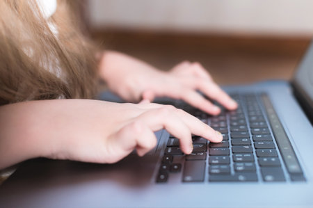 Closeup shallow depth of field of a little girls hand on a laptop keyboard. The concept of using the younger generation of gadgetsの写真素材