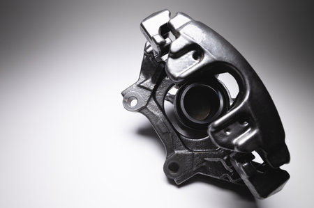 Brake caliper in black. A spare part for a car brake system on a gray background in high contrast.
