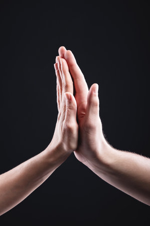 High five male and female hand gesture on black background. Friendship of men with womenの写真素材