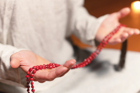 close-up of a male practitioners hand sitting in lotus position in a dark meditation room with a rosary in his handsの写真素材