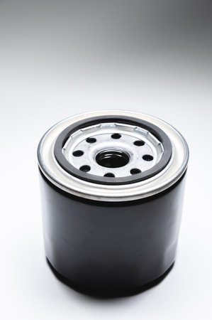 Black new oil filter in contrasting light on a black and white background. Wide angle