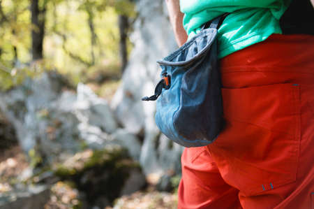 Close-up of a bag of magnesia hanging on a climbers belt in the forest on a trainer. pouch of...