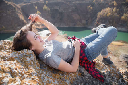 Attractive caucasian young woman lies on a rock in the mountains against the background of a...