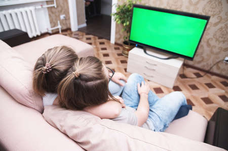 young couple sits in the room on the couch and looks at the TV screen, top view