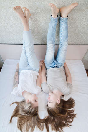 Young attractive heterosexual couple man and woman lie on the bed in the bedroom dressed in casual...